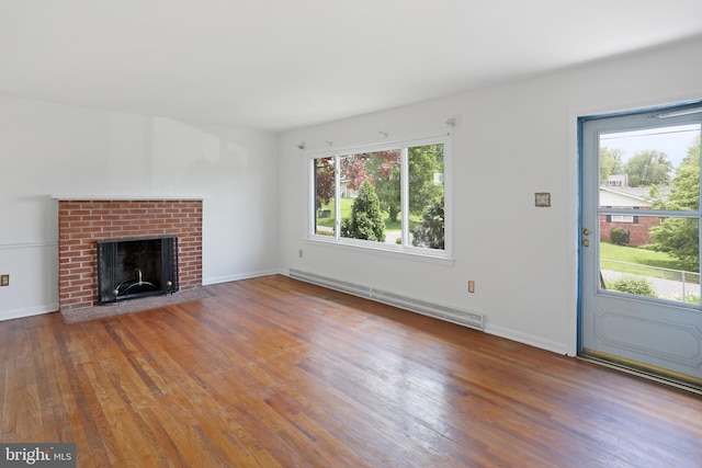 unfurnished living room with baseboard heating, healthy amount of natural light, wood finished floors, and a fireplace