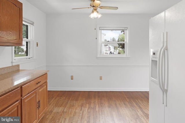 unfurnished dining area with light wood-type flooring, ceiling fan, and baseboards