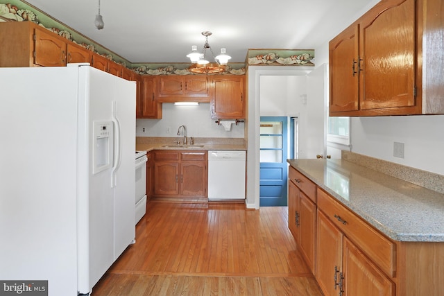 kitchen featuring white appliances, a sink, a chandelier, light countertops, and light wood finished floors