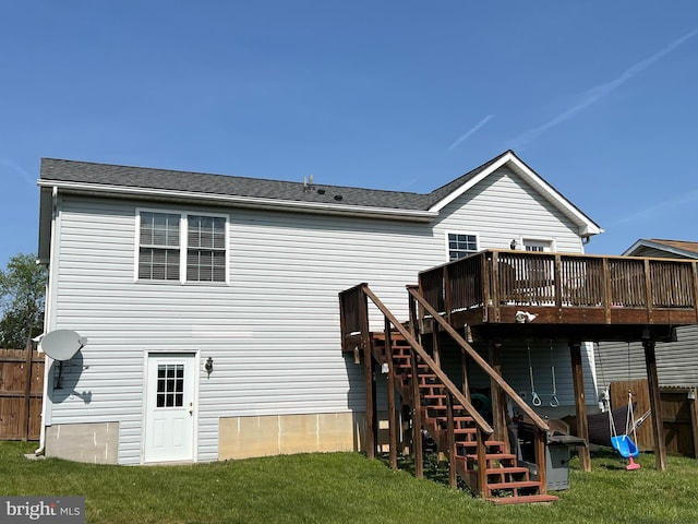 back of property with fence, a deck, roof with shingles, stairs, and a lawn