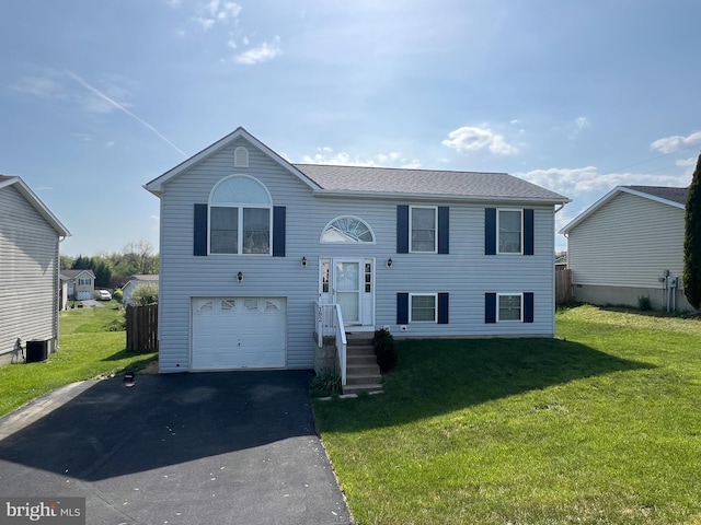 raised ranch with an attached garage, aphalt driveway, and a front yard