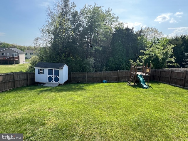 view of yard featuring a fenced backyard, a storage unit, an outbuilding, and a playground