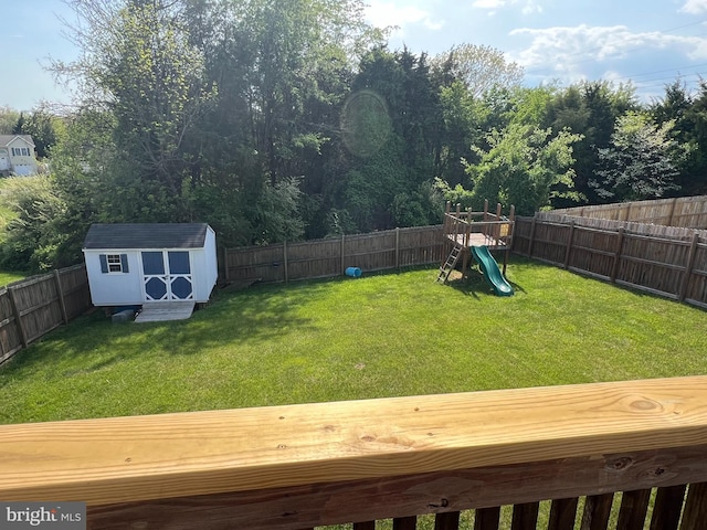 view of yard with a playground, a storage unit, an outbuilding, and a fenced backyard