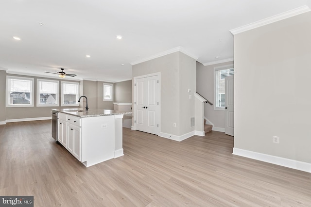 kitchen with a sink, baseboards, ornamental molding, and white cabinets