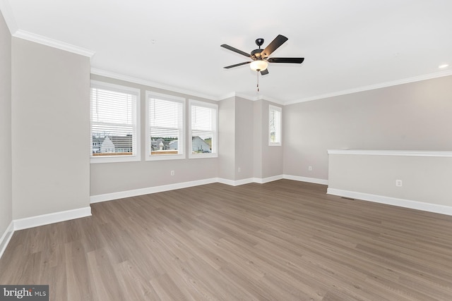 empty room with baseboards, ornamental molding, ceiling fan, and wood finished floors