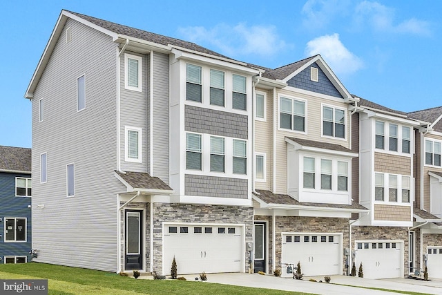view of property featuring an attached garage, driveway, and stone siding