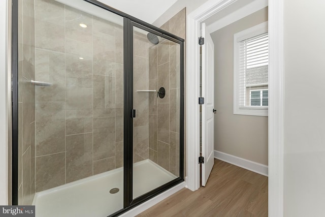 full bathroom with baseboards, wood finished floors, and a shower stall