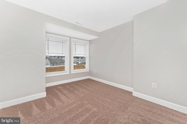 spare room featuring carpet floors and baseboards