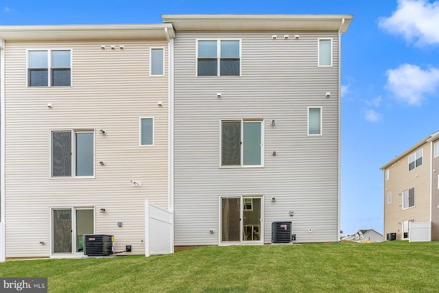 rear view of house featuring a lawn and central AC unit