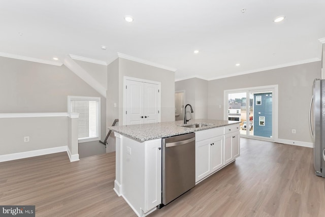 kitchen with a sink, light wood finished floors, stainless steel appliances, baseboards, and a center island with sink