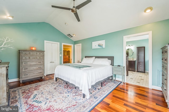 bedroom with lofted ceiling, baseboards, ensuite bathroom, visible vents, and wood finished floors