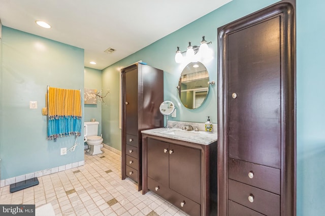bathroom featuring toilet, vanity, visible vents, tile patterned flooring, and baseboards