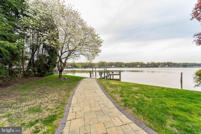 dock area with a lawn and a water view