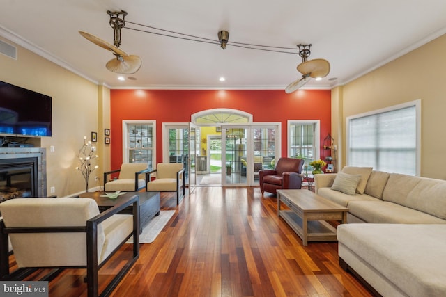 living room featuring recessed lighting, hardwood / wood-style flooring, ornamental molding, and a glass covered fireplace