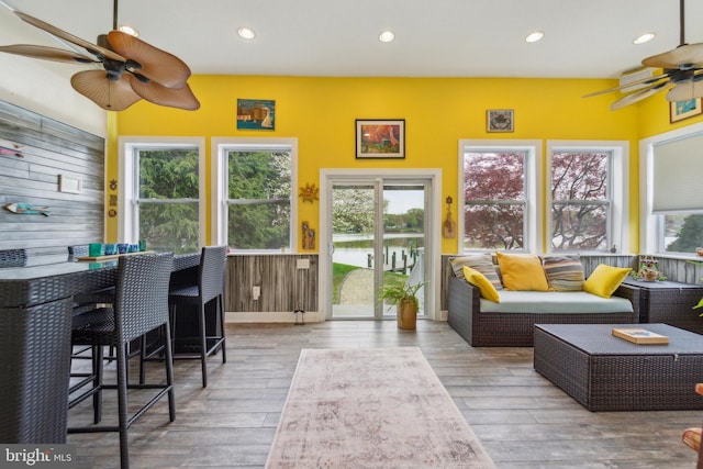sunroom with a deck with water view, wood finished floors, and recessed lighting