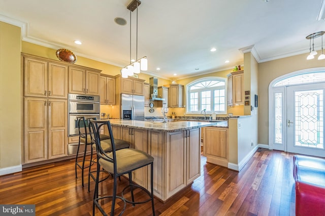 kitchen with light stone countertops, dark wood-style flooring, ornamental molding, wall chimney range hood, and stainless steel appliances