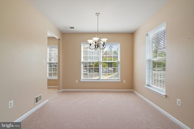 unfurnished dining area with visible vents, baseboards, a notable chandelier, and light colored carpet