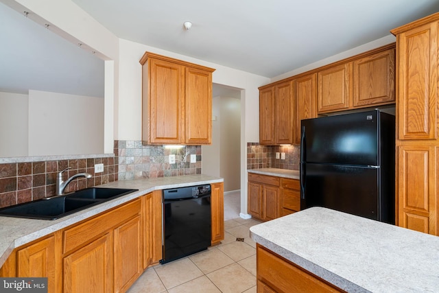 kitchen with a sink, decorative backsplash, black appliances, and light countertops