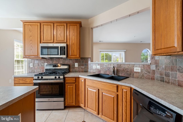 kitchen featuring a sink, appliances with stainless steel finishes, brown cabinetry, and backsplash