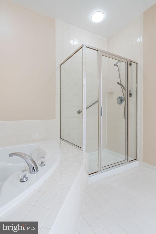 bathroom featuring tile patterned floors, a stall shower, and a bath