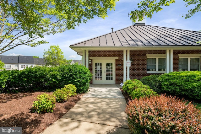 entrance to property with brick siding, metal roof, french doors, and a standing seam roof