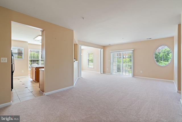 unfurnished room with baseboards, light tile patterned flooring, and light carpet