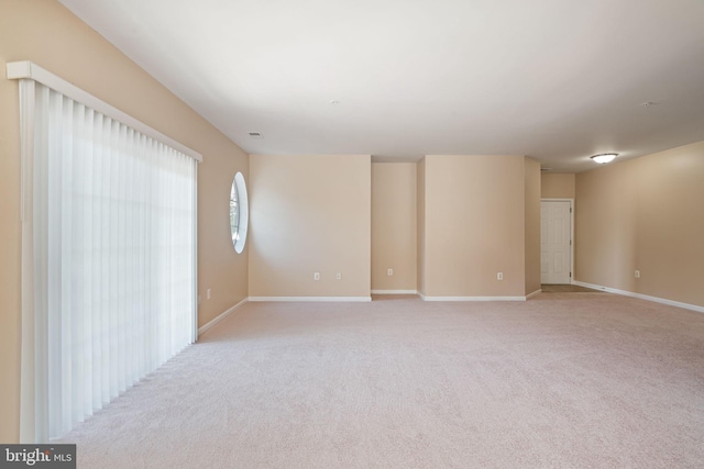 spare room featuring baseboards and light carpet