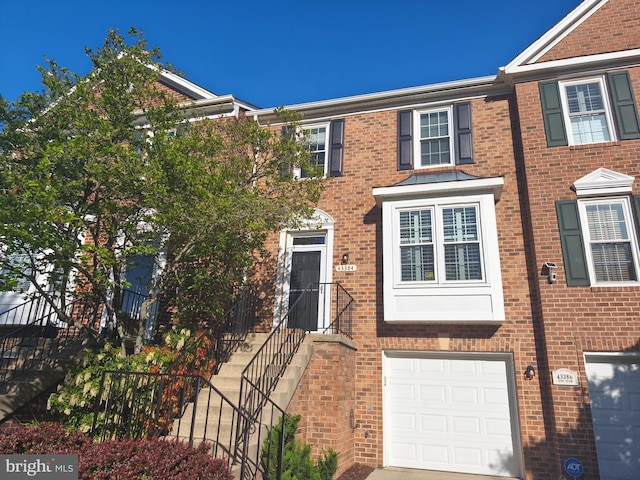 multi unit property with brick siding and an attached garage