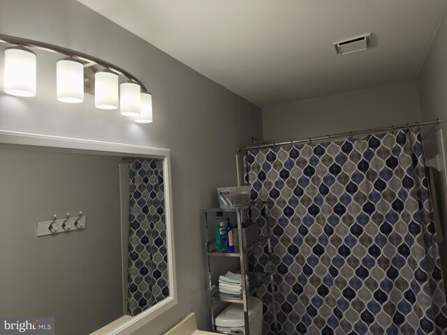 bathroom featuring toilet, visible vents, and a shower with shower curtain