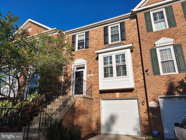 townhome / multi-family property with a garage, concrete driveway, and brick siding