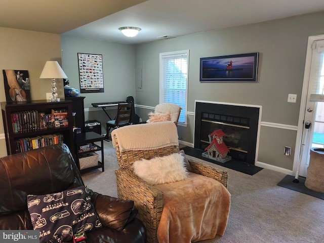 living room featuring baseboards, carpet flooring, a fireplace with flush hearth, and visible vents