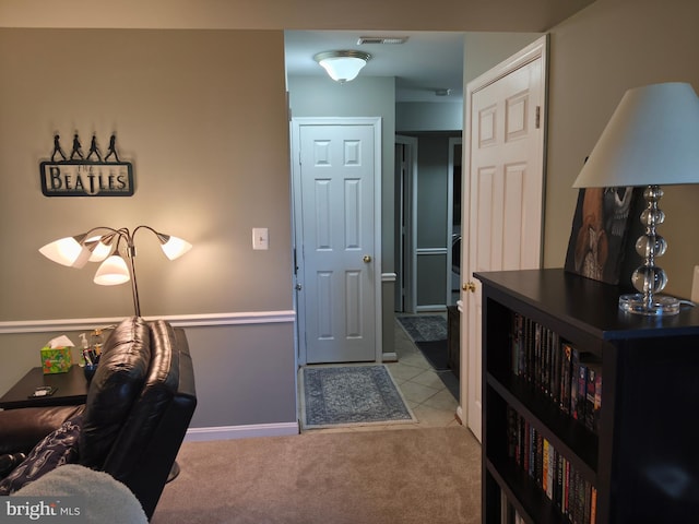 foyer entrance featuring baseboards, visible vents, light carpet, and light tile patterned floors