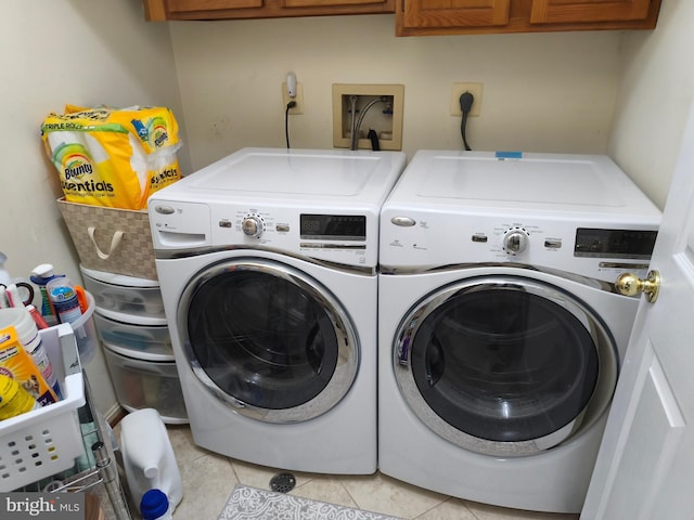 laundry area with separate washer and dryer, cabinet space, and light tile patterned floors