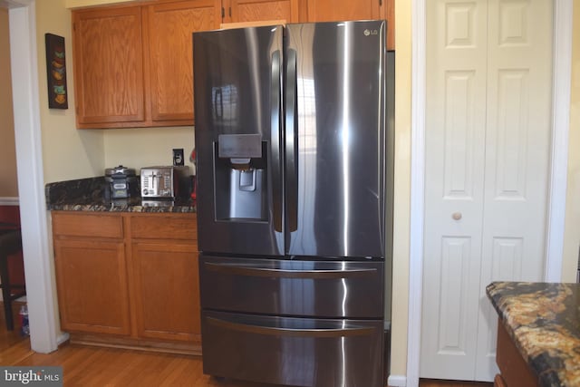 1716 Pebble Beach Dr, Bowie, MD 20721 - kitchen featuring stainless steel fridge, light wood-style floors, brown cabinetry, and dark stone countertops