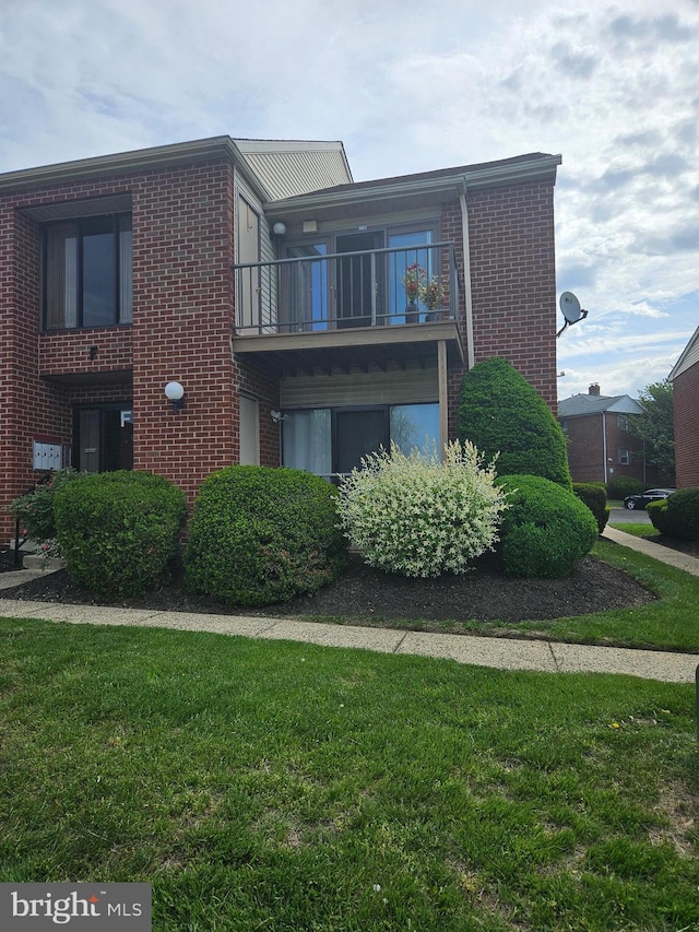 exterior space with a yard, brick siding, and a balcony