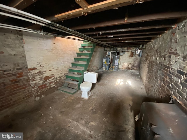 unfinished below grade area featuring stairway, water heater, and heat pump water heater