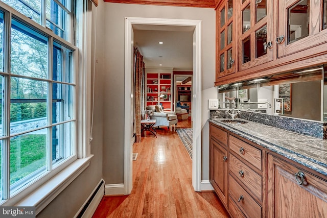 bar with crown molding, baseboards, a sink, and light wood finished floors