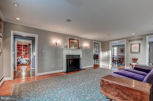 living room featuring crown molding, light wood finished floors, baseboards, and a fireplace