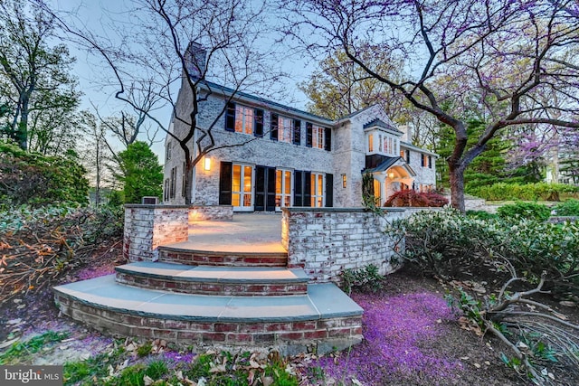 rear view of property featuring a porch, a chimney, and brick siding