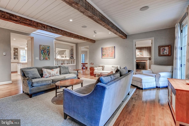 living room featuring wooden ceiling, beamed ceiling, a brick fireplace, and hardwood / wood-style flooring