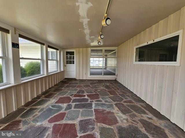 unfurnished sunroom featuring track lighting and a wealth of natural light