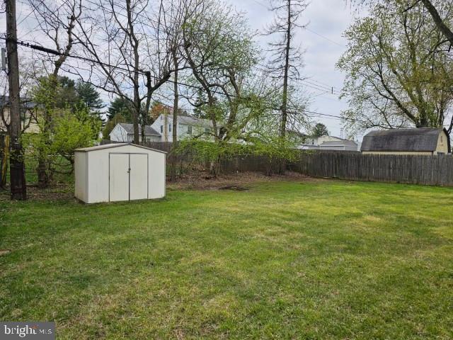 view of yard featuring fence, an outbuilding, and a storage unit
