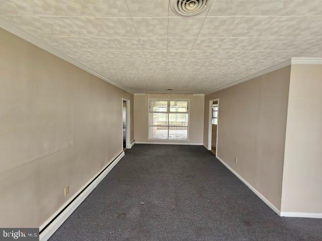 spare room featuring visible vents, a baseboard radiator, baseboards, and dark carpet