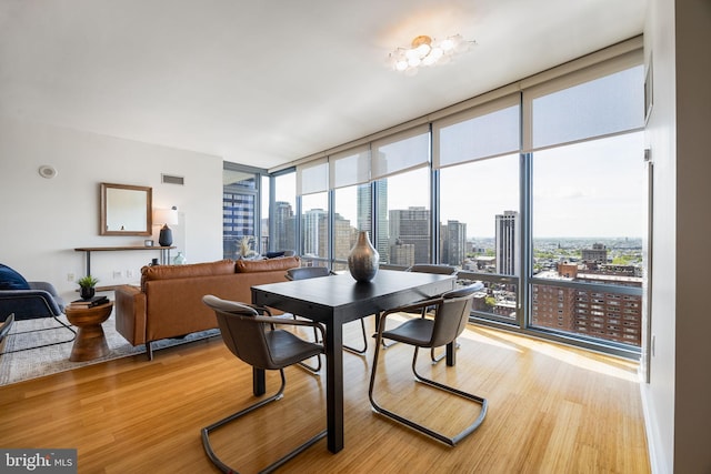 dining room featuring expansive windows, a view of city, and light wood finished floors