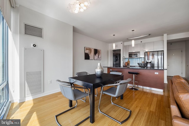 dining room featuring a heating unit, visible vents, baseboards, and light wood finished floors