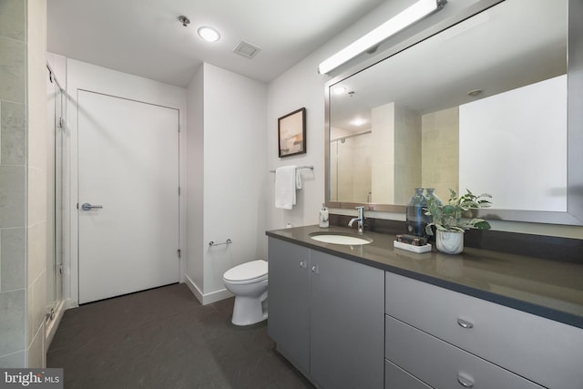 bathroom with vanity, a shower with shower door, toilet, and visible vents