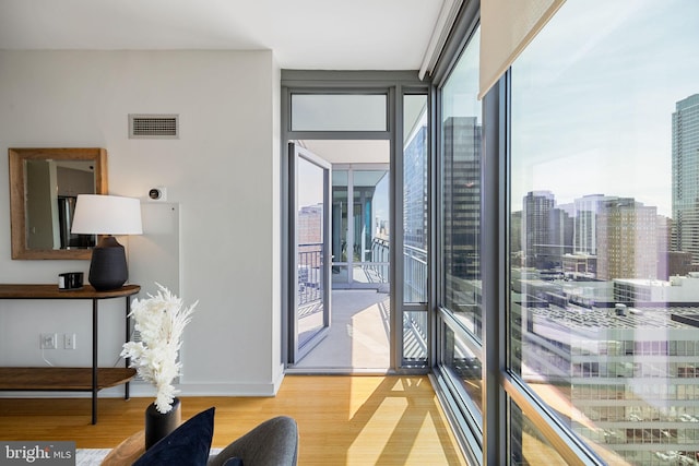 interior space featuring a healthy amount of sunlight, a wall of windows, light wood finished floors, and visible vents