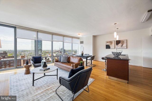living room featuring light wood-style floors, baseboards, floor to ceiling windows, and visible vents