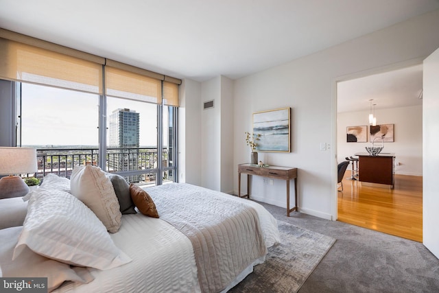 carpeted bedroom featuring baseboards, access to outside, expansive windows, and visible vents