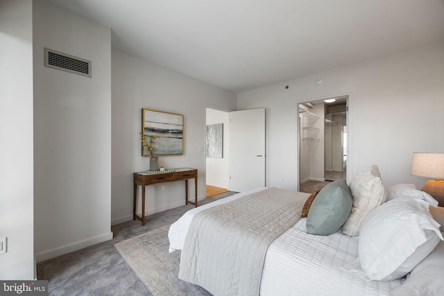 bedroom with visible vents, baseboards, carpet floors, and a walk in closet